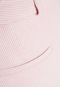 Pink and white striped fabric with a smooth texture; features a back pocket with a rounded edge and a curved waistband design.