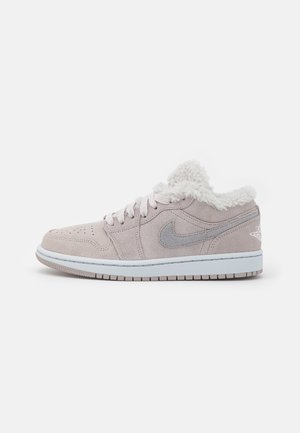 Lavtop beige ruskind sneaker med grå Nike swoosh, hvide snørebånd, hvid sål og blød hvid fleeceforet krave.