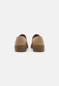 Brune suedesko med lav profil og rund tå. Teksturert overdel, solid gummisåle og minimale sømdetaljer. Klassisk design.