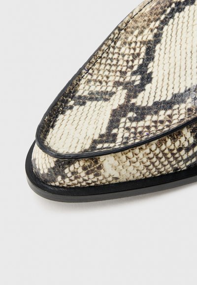Hegyes orrú cipő texturált fekete-fehér kígyóbőr mintával, sima fekete szegéllyel és lapos talppal.