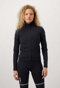 Čierna cyklistická bunda s dlhým rukávom, vysokým golierom, predným zipsom a jemným logom na ramene, vyrobená z hladkého, pružného materiálu.