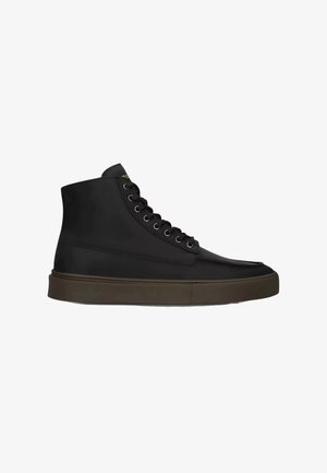 Zapatilla deportiva alta de cuero negra con cordones negros y suela gruesa de goma marrón oscura, vista lateral sobre fondo blanco.