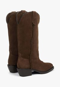 Hnědé semišové kovbojské boty s mírně špičatou špičkou, dekorativními volánky podél švu a pevným blokovým podpatkem.