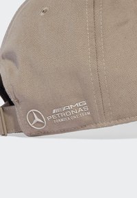 Beige cap lavet af bomulds-twill, med broderede hvide logoer for AMG og Petronas, samt en struktureret skygge med en buet form.