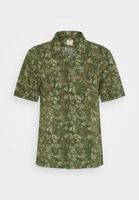 Camicia verde a maniche corte con stampa di foglie e fiori, realizzata in tessuto leggero con chiusura frontale a bottoni e etichetta sul colletto.