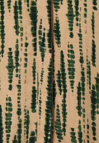 Tissu en velours avec une base beige et des rayures verticales vert foncé, présentant des motifs texturés de largeurs et de formes variées.