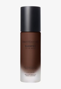Bruine glazen fles met een zwarte matte dop. Etiket vermeldt "bareMinerals" en "BAREPRO 24 HR WEAR" met witte tekst. Vloeibare foundation binnenin, halfdoorzichtig.