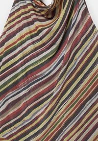 Lagani materijal s dijagonalnim prugama u crvenoj, zelenoj, bež, crnoj i bijeloj boji, prikazuje meke nabore i nabubljenu teksturu.