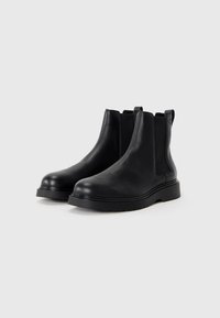 Black leather ankle boots with a textured finish, elastic side panels, and a thick rubber sole. Features pull tabs for easy wear.