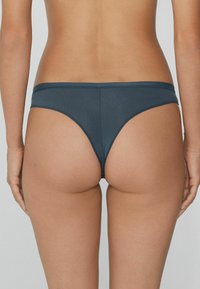 Dunkelblauer Bikiniunterteil aus weichem Stoff, mit einem minimalistischen Design, niedrig geschnitten und mit schmalen Seiten für reduzierte Abdeckung.