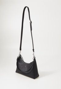 Schwarze Lederhandtasche mit einer geschwungenen Silhouette. Sie verfügt über einen Ketten- und Ledertragegurt, hat eine glatte Textur und genähte Details entlang der Kanten.