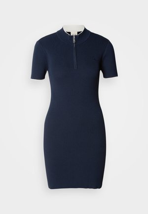 Marineblauwe geribbelde gebreide jurk met korte mouwen, hoge kraag en een centrale rits. Soepele textuur, aansluitende silhouet en subtiele logodetail.