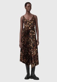 Pleatattu midi-pituinen mekko rohkeassa oranssin ja mustan eläinkuosissa. Ominaisuuksina ohuet hihnat ja istuva vyötärö. Yhdistettynä mustiin polvimittaisiin saappaisiin.