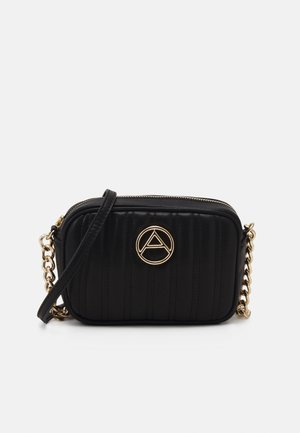 Mustayt Siyah dikişli çapraz çanta, altın yuvarlak logosu, zincir askısı ve fermuarlı kapamasıyla dikkat çekiyor. Doku için dikey dikişler içeriyor.