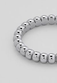 Zilverkleurige metalen armband met gladde, ronde kralen die zijn gerangschikt in een doorlopende band en het licht weerkaatsen met een glanzende afwerking.