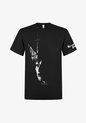 Camiseta negra con un gráfico blanco de una cara llevando una corona con cuernos en la parte delantera y texto gótico blanco en la manga derecha.