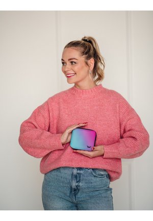 Knitted pink sweater, high neck, with relaxed fit. Holding a blue and pink gradient zippered pouch with logo in a minimalist design.