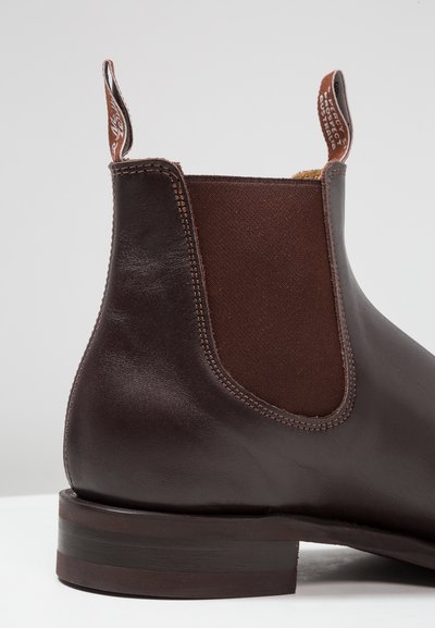 Brown leather Chelsea boot featuring elastic side panels, a loop tab, contrasting stitching, and a low stacked heel.