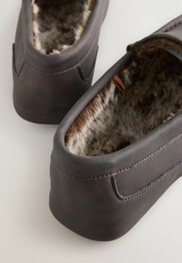 Donkerbruine leren schoenen met een zachte, lichtbruine bontvoering, die een minimalistisch ontwerp, een ronde vorm en subtiele stiksels bevatten.