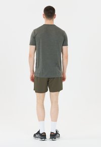 Dunkelgraues meliertes T-Shirt mit kurzen Ärmeln, kombiniert mit olivgrünen Shorts. Das Modell trägt schwarze Sneakers mit weißen Socken. Schlichter Hintergrund.