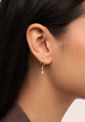 Pendiente de aro de oro con un colgante que presenta una piedra en forma de marquesa y dos pequeños acentos redondos. Textura suave, diseño elegante.