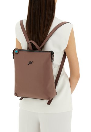 Zaino in pelle marrone con texture, spalline regolabili, chiusura con zip e un piccolo accento blu sul tirante della zip. Design minimalista.