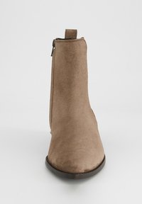 Hnědá kotníková bota z semiše s hladkou texturou, zaoblenou špičkou, poutkem na zadní straně a bočním zipem; plochá gumová podrážka.