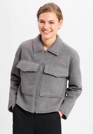 Graue, strukturierte Jacke mit einem Reißverschluss, zwei Fronttaschen und einem kragenförmigen Nacken, mit einer cropped, boxy Silhouette.