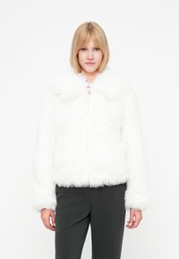 Giacca in pelliccia sintetica bianca con una texture morbida e soffice, maniche lunghe e colletto ampio. Chiusura centrale con zip.