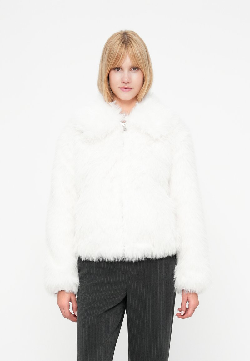 Giacca in pelliccia sintetica bianca con una texture morbida e soffice, maniche lunghe e colletto ampio. Chiusura centrale con zip.