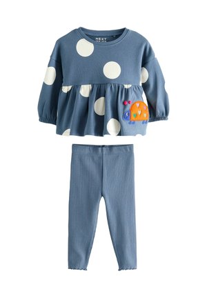 Haut en coton bleu avec des pois blancs, manches bouffantes et un escargot brodé. Associe à un legging bleu côtelé.