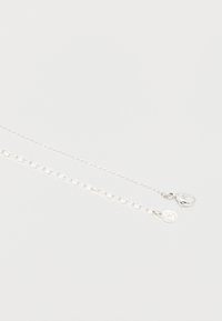 Δύο ασημένιες αλυσίδες με διαφορετικά σχέδια συνδέσμων, η μία με κούμπωμα αστακού και η άλλη με ένα μικρό στρογγυλό ταμπελάκι επισυναπτόμενο.