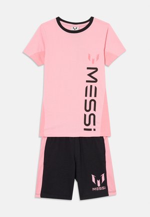 To-delt atletisk sæt med en lyserød t-shirt med korte ærmer, der har sort "MESSI" tekst og logo, kombineret med sorte shorts med pink striber og logo.