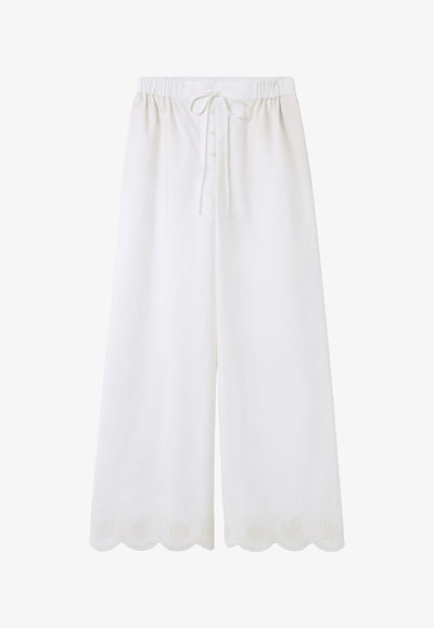 Pantalon large blanc avec une taille élastique, cordon de serrage ajustable et broderie décorative en forme de vagues sur l'ourlet. Des boutons descendent le long du devant.