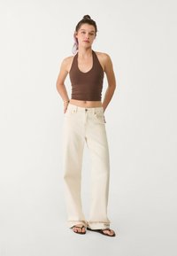 Ruskea halter-top, beige leveät lahkeet farkut ja mustat flip-flopit. Asusteessa on yksinkertainen muotoilu, rento istuvuus ja sileät tekstuurit.