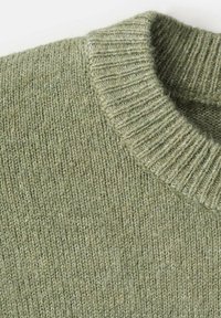 Pletiva ženske zeleni pulover u prigušenoj boji, s rebrastim okruglim izrezom i mekanim, teksturiranim materijalom. Dizajn je jednostavan s glatkom završnom obradom.