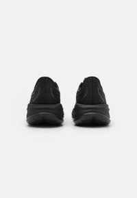 Scarpe sportive nere con tomaia in tessuto testurizzato, suole nere imbottite e dettagli di design discreti. La vista posteriore mette in evidenza il tallone e il logo.