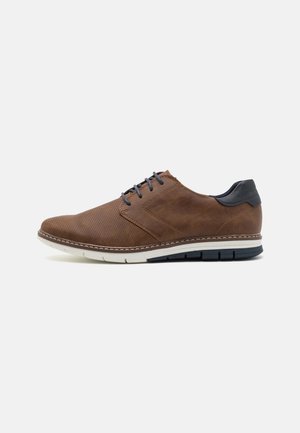 Zapatos de cuero marrón con textura perforada, cordones grises y un tacón oscuro en contraste. Presenta una suela blanca y gris con detalles de costura.