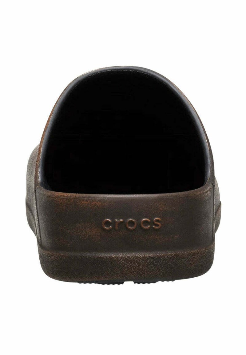 Dichte bruine Crocs-klompen gezien vanaf de achterkant met "crocs" branding op de hielband.