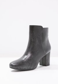 Botín negro con estampado de serpiente, acabado brillante, puntera redonda y tacón alto y grueso. Textura suave con exterior estampado.