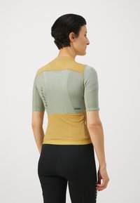Kurzarm-Radsporttrikot in Hellgrün und Gelb, mit einem strukturierten Mesh-Muster und einer Rückentasche, entworfen für Passform und Belüftung.