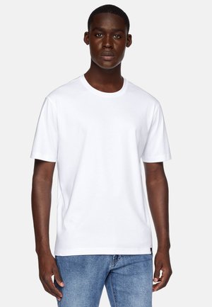 White cotton t-shirt with short sleeves and a round neckline, worn with blue denim jeans, featuring a simple design and smooth texture.