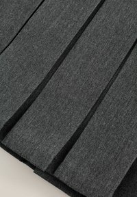 Grå plisserad tyg med en texturerad yta, som har vertikala plisseringar och en slät yta. Materialet verkar hållbart och tjockt.