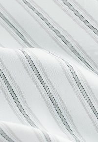 Tissu blanc avec des rayures alternées gris clair et bleu marine, présentant un motif de tissage texturé et une finition lisse.