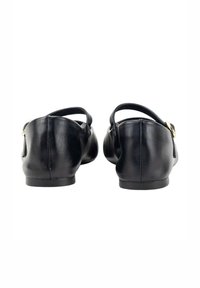 Zapatos de cuero negros con un tacón bajo y una correa en el tobillo. Presenta un acento de hebilla dorada en la correa. Textura suave con una forma redondeada.