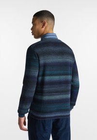Maglione lavorato a maglia con strisce orizzontali negli colori blu scuro, teal e blu navy. Collo a girocollo, maniche lunghe, polsini e orlo a coste.