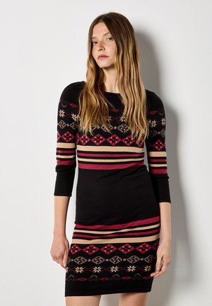 Czarna dzianinowa sukienka z długimi rękawami, z kolorowymi geometrycznymi wzorami i poziomymi paskami w czerwonym i beżowym kolorze, dopasowana sylwetka.