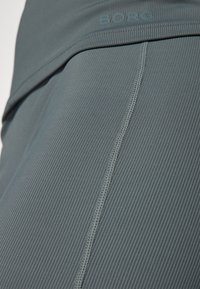 Szürke bordázott sportleggings magas derékkal, lapos varratokkal és diszkrét logóval a derékpánt közelében. Puha tapintású.
