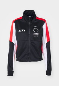 Nike-jacka med svart kropp och röda och vita ärmar, hög krage, dragkedja fram och grafiska mönster på bröstet. Tillverkad av elastiskt material.