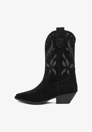 Czarny kowbojski but zamszowy z srebrnymi ćwiekami i obcasem o średniej wysokości, skośnym, z uchwytem do ściągania na szczycie.